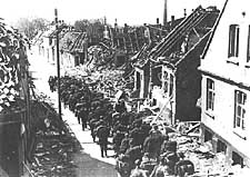 Avvpnade tyska trupper marscherar mot hamnen i genom det bombade Rnne